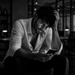 Man sitting alone in a dark office at night looking at his phone, illustrating depression and divorce