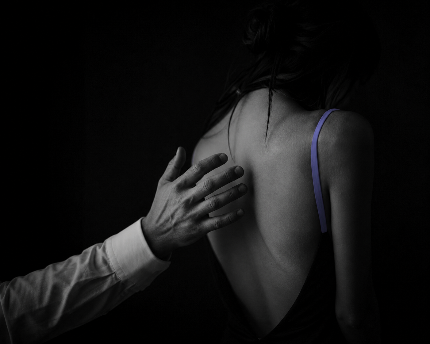 Woman turned away from a man's reaching hand in moody black and white, evoking the question of whether to forgive a partner for cheating