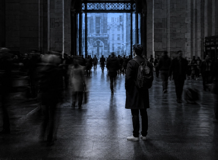 Man standing motionless in a blurred, moving crowd, illustrating the isolation emotional support is meant to address