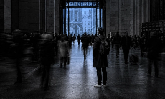 Man standing motionless in a blurred, moving crowd, illustrating the isolation emotional support is meant to address
