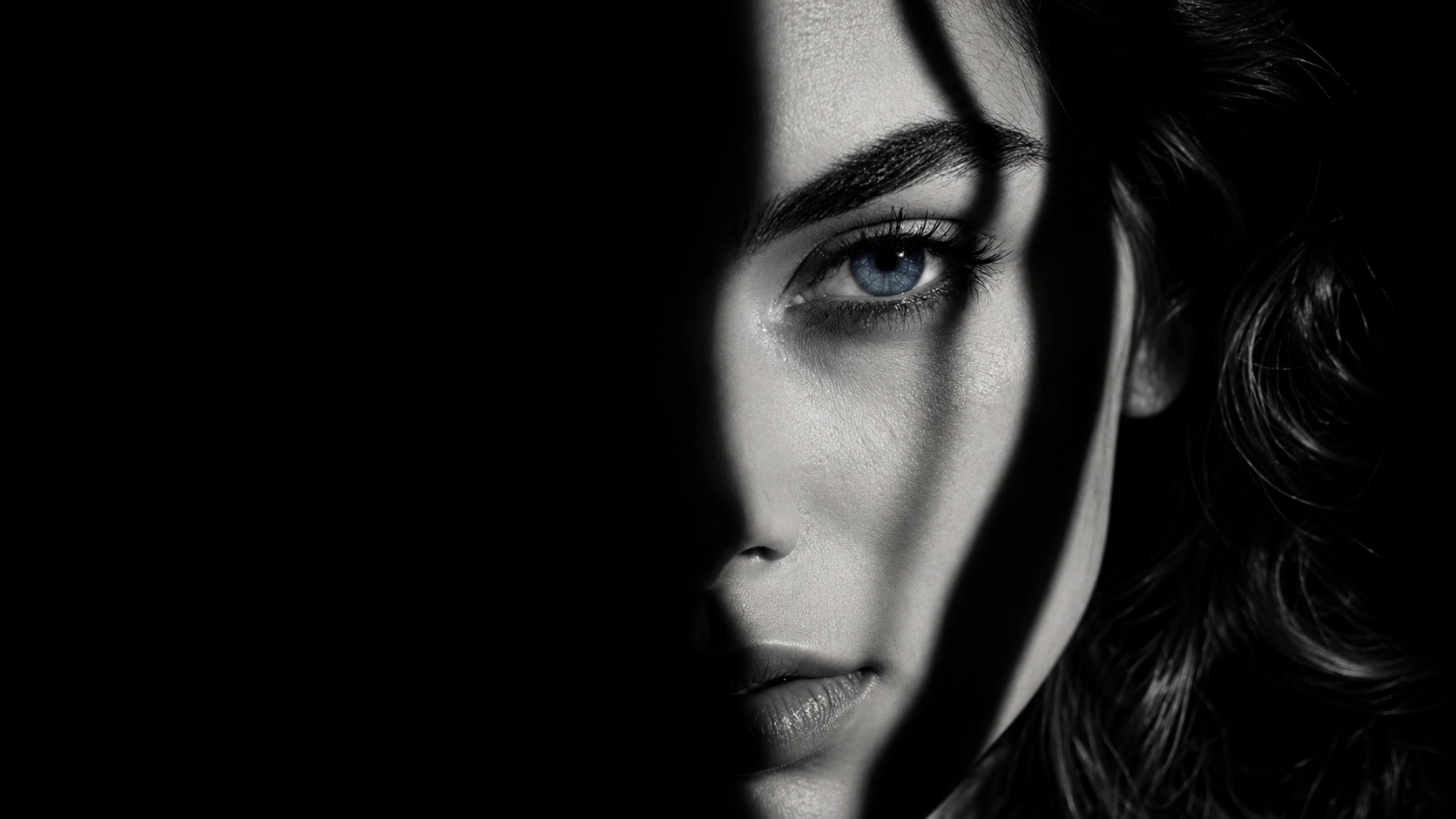 Woman's face half in shadow with a single tear, capturing the isolation of betrayal trauma