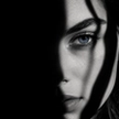Woman's face half in shadow with a single tear, capturing the isolation of betrayal trauma