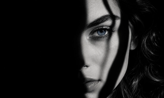 Woman's face half in shadow with a single tear, capturing the isolation of betrayal trauma