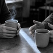 Two people talking over coffee at a wooden table after one of the divorce support groups near me