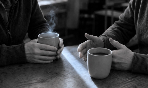 Two people talking over coffee at a wooden table after one of the divorce support groups near me