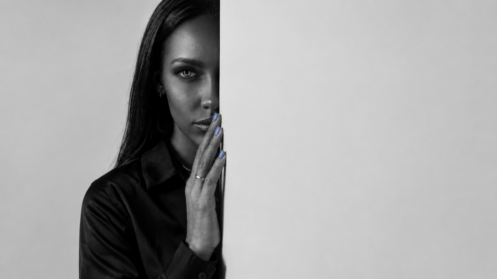 Woman half-hidden behind a wall weighing reconciliation after infidelity, hand raised to her lips.