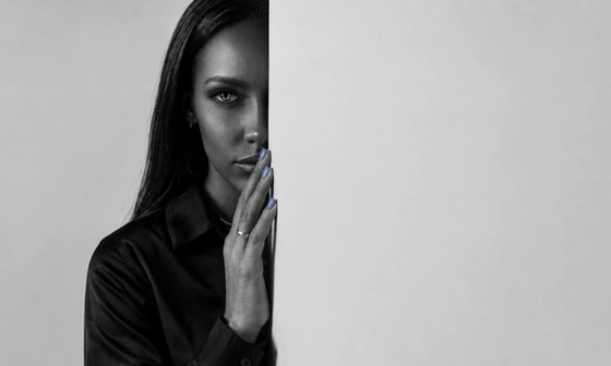 Woman half-hidden behind a wall weighing reconciliation after infidelity, hand raised to her lips.