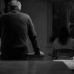 Older man and younger woman apart in a dim kitchen at night, illustrating the distance in age gap relationships