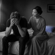 A distressed man comforted by his partner on the edge of a bed, a scene about how to know if a cheater will cheat again.