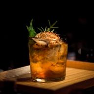 Cocktail ambré garni d’agrumes et d’herbes fraîches