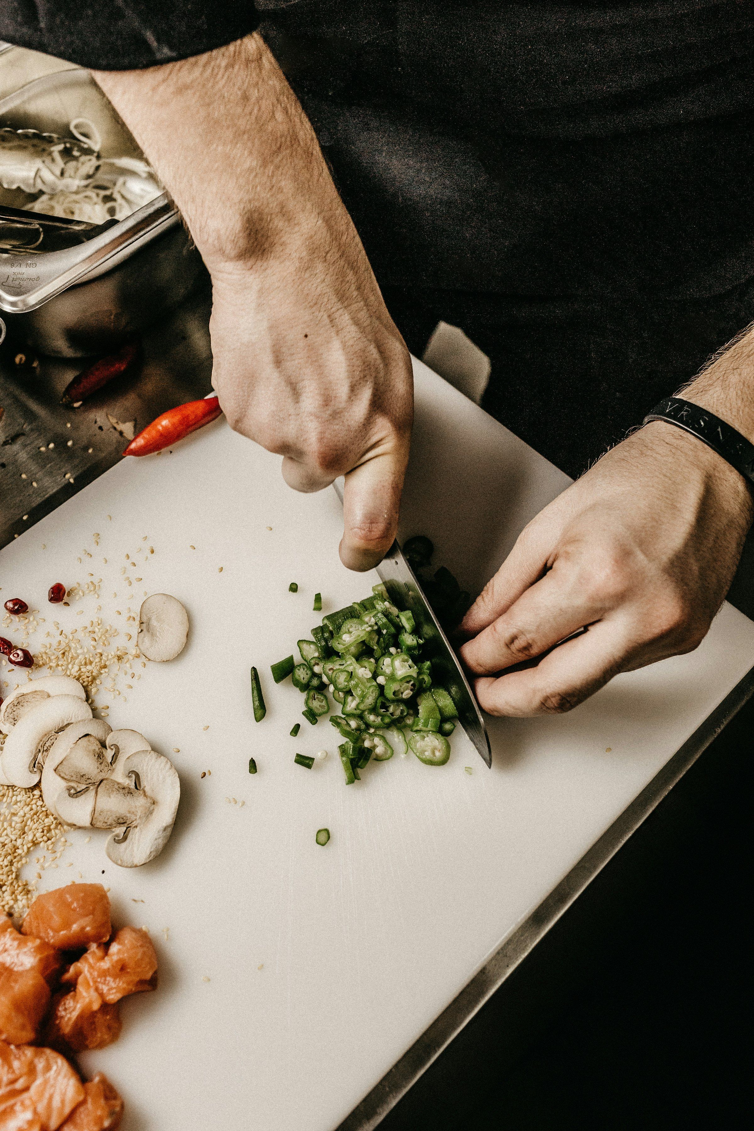 Mains du cuisinier taillant des légumes frais au couteau sur une planche