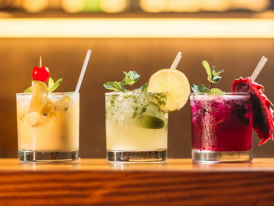 Trois cocktails colorés alignés sur le comptoir du bar