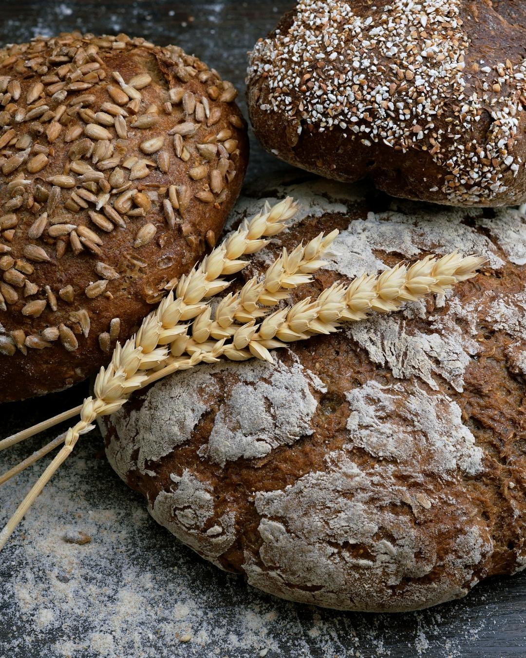 Miches de pain au levain croustillantes posées sur une planche avec des épis de blé