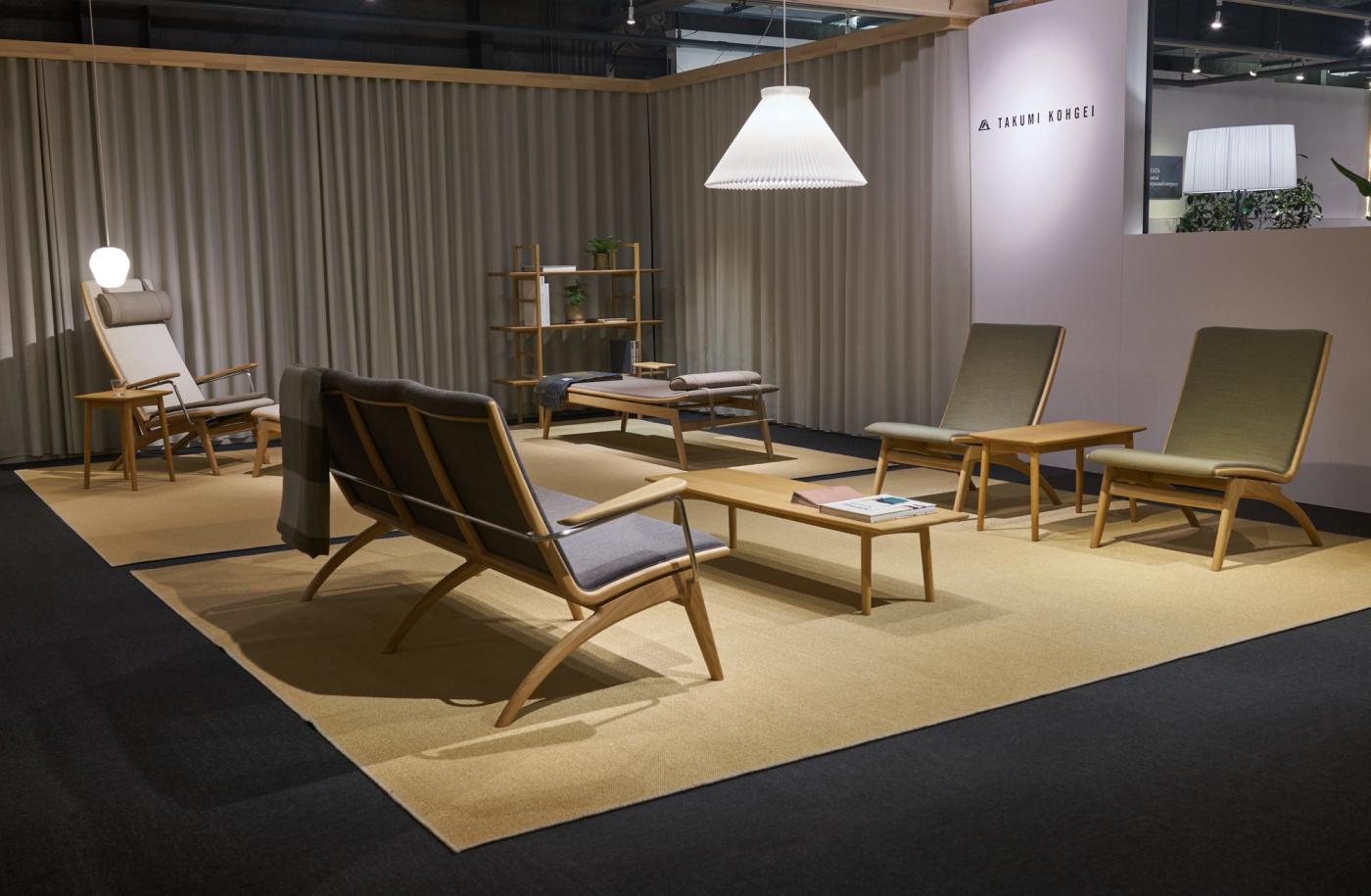 GAZE sofa, lounge chairs and high-back chair in oak with grey and green upholstery, arranged around a low oak table on a beige rug, with a white pendant lamp and grey curtains.