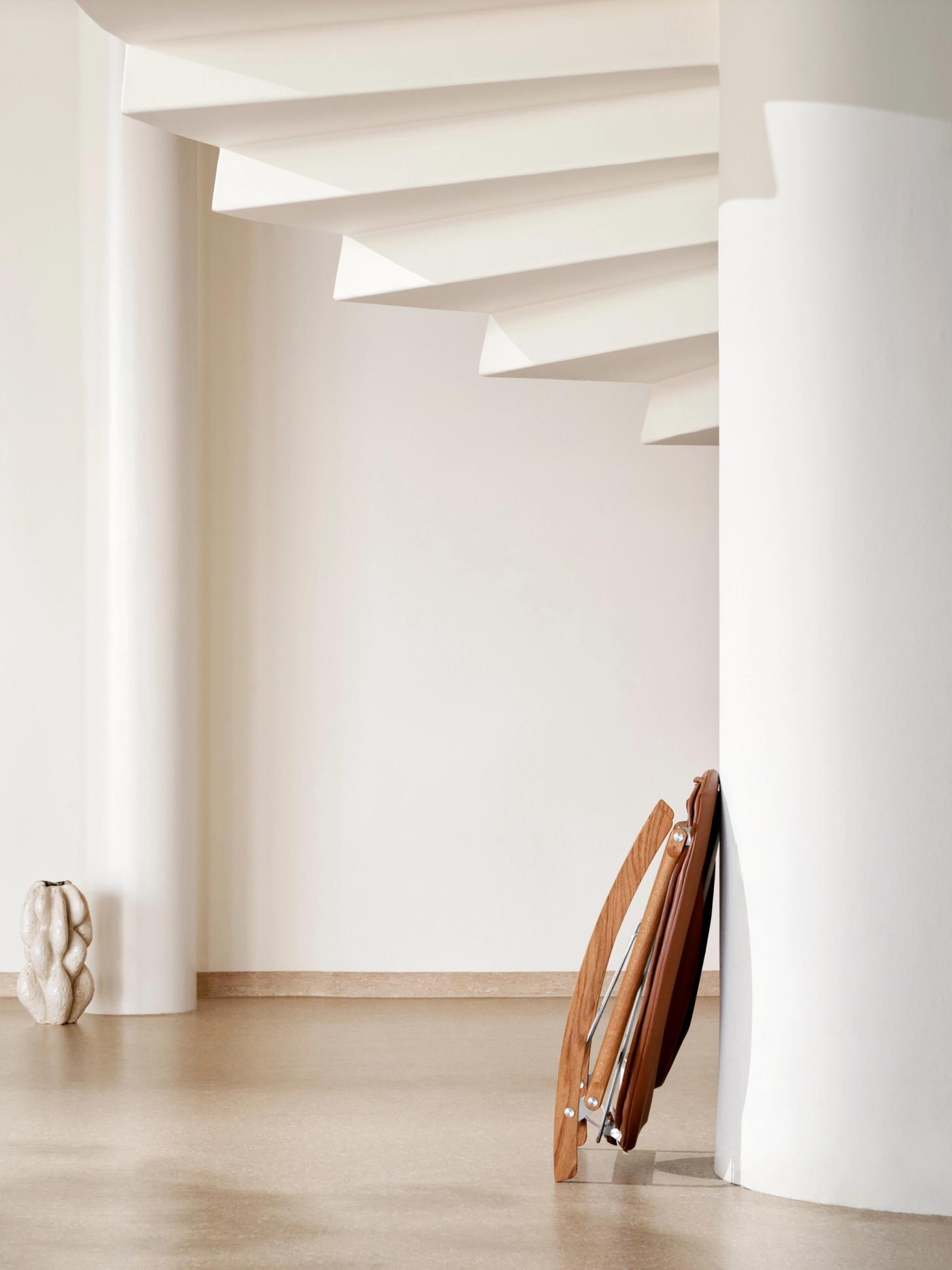 Rocking Nest Chair by Carl Hansen & Søn — a foldable rocking chair in walnut wood with a suspended canvas seat and steel cable details, shown in profile on a white background.