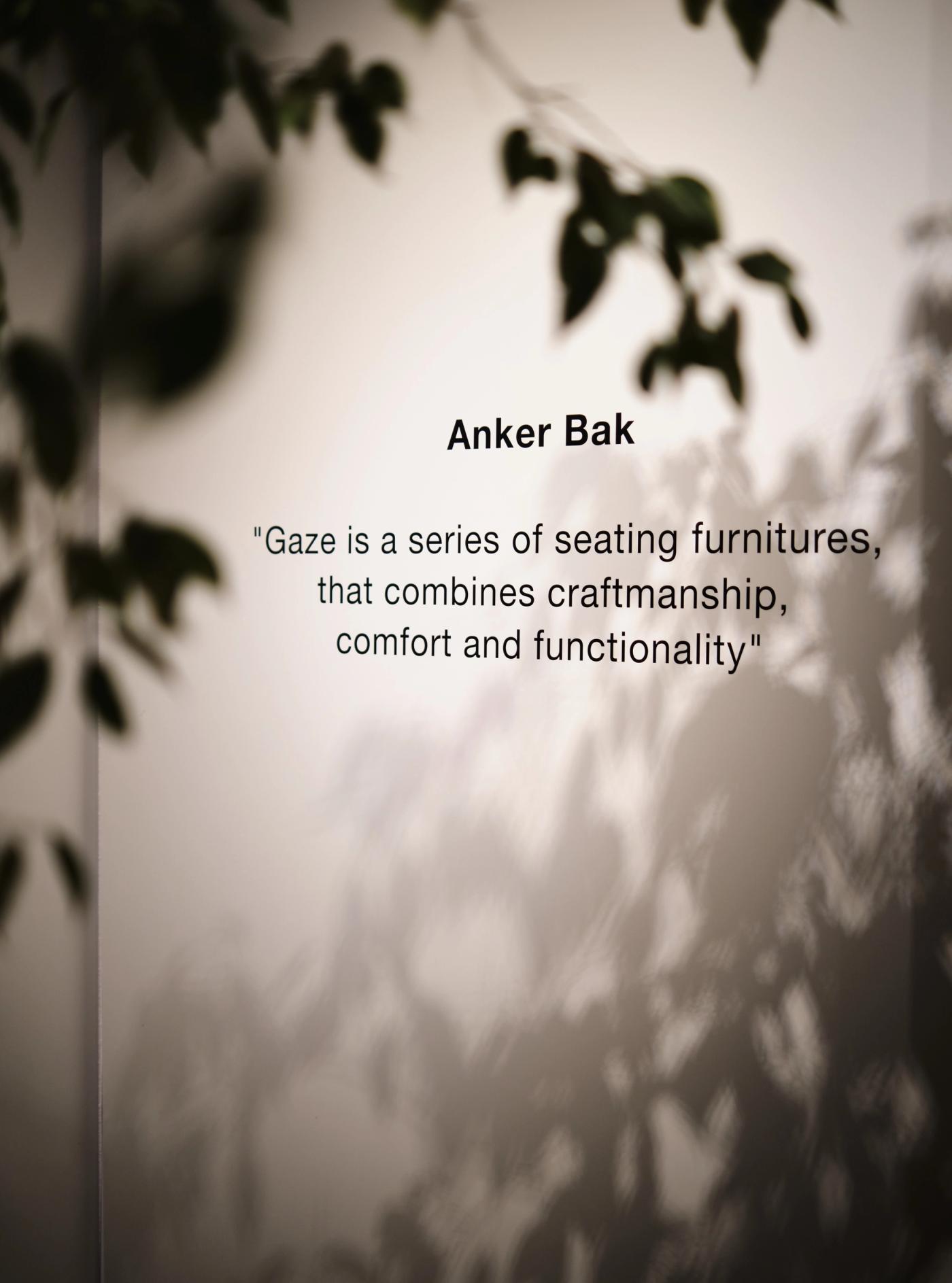 Poster with the text "Anker Bak" and the quote "Gaze is a series of seating furniture that combines craftsmanship, comfort and functionality", set against soft shadows of leaves on a light background.