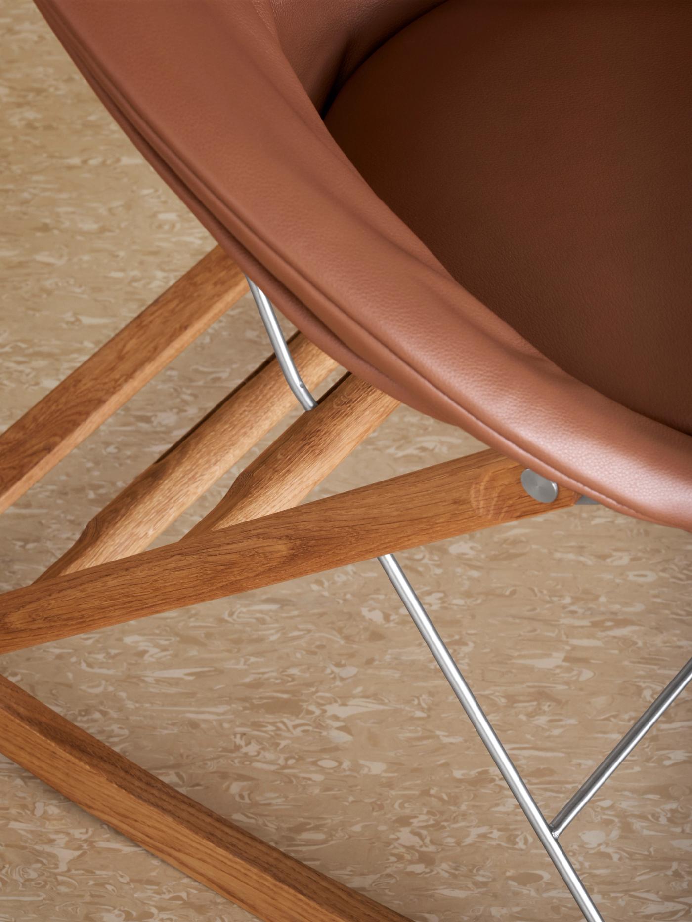 Rocking Nest Chair by Carl Hansen & Søn — a foldable rocking chair in walnut wood with a suspended canvas seat and steel cable details, shown in profile on a white background.
