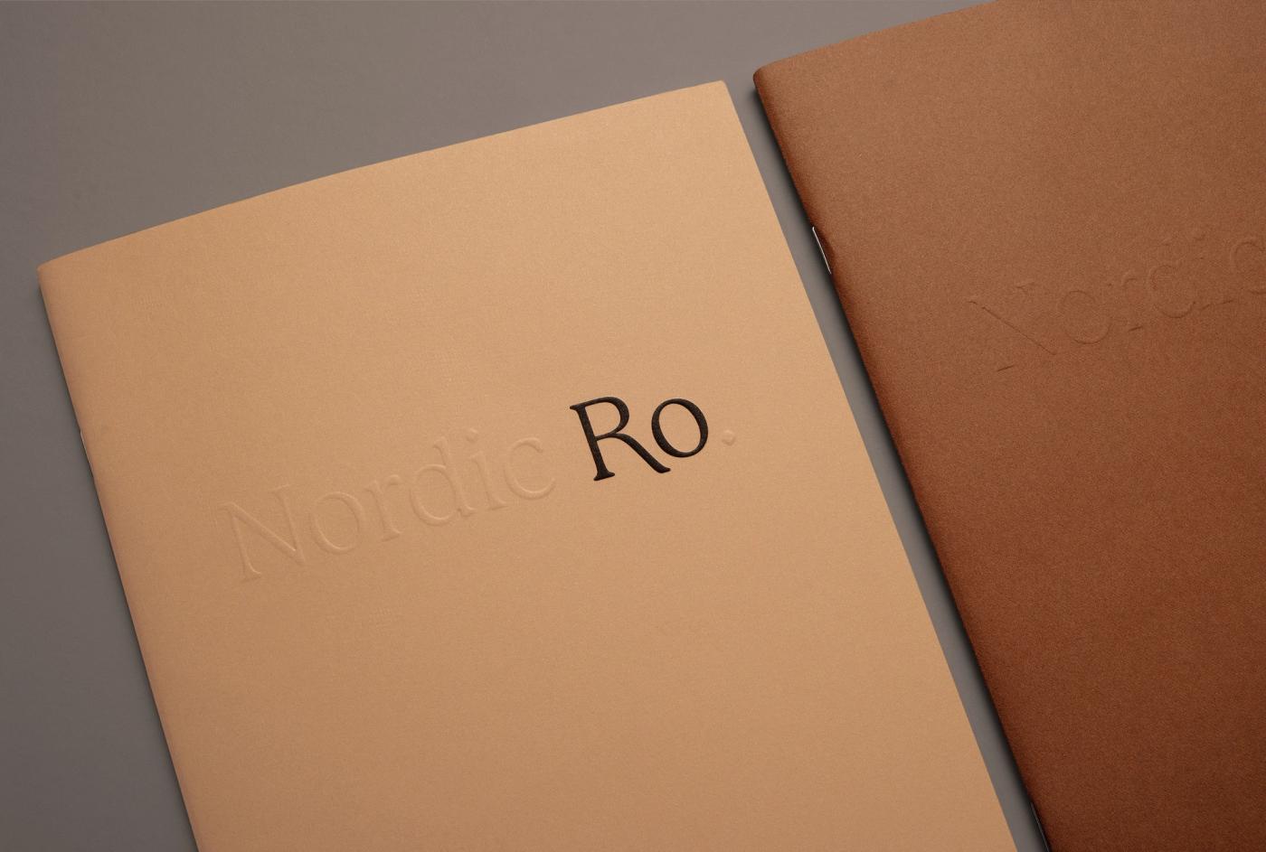 Close-up of the peach Ro catalogue cover with an embossed "Nordic" and a large "Ro" title, beside a brown catalogue cover.