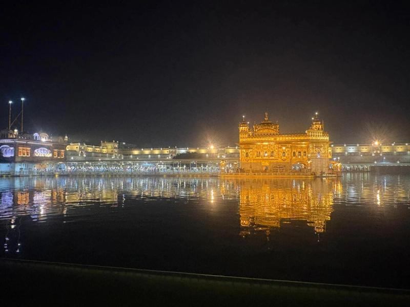 Der Goldene Tempel in Amritsar bei Nacht, gespiegelt im Wasser