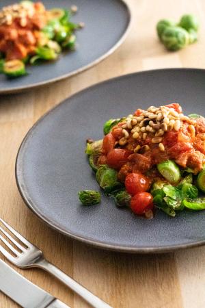 Tomatsovs med salsiccia serveret på stegt rosenkål