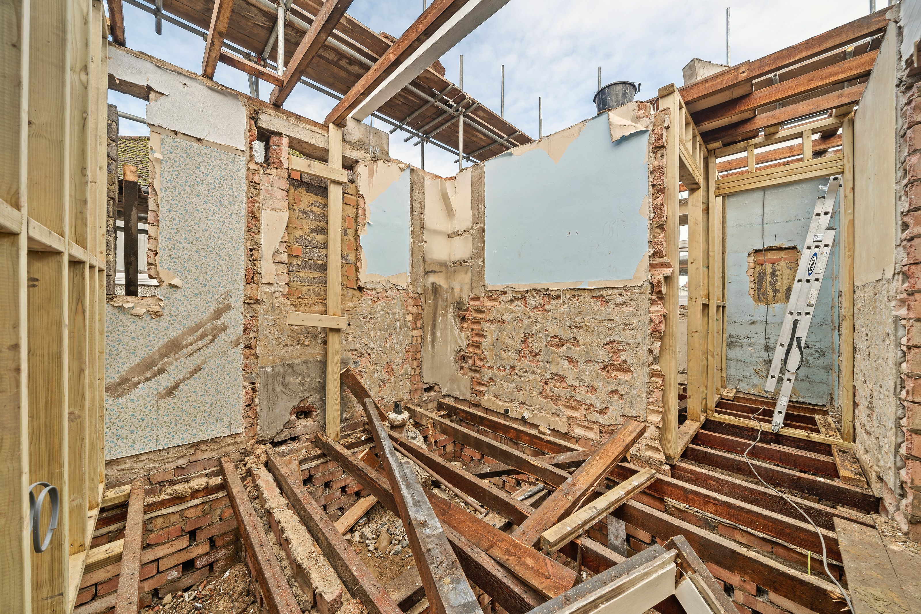 New timber studwork between old brick walls, with the roof open above