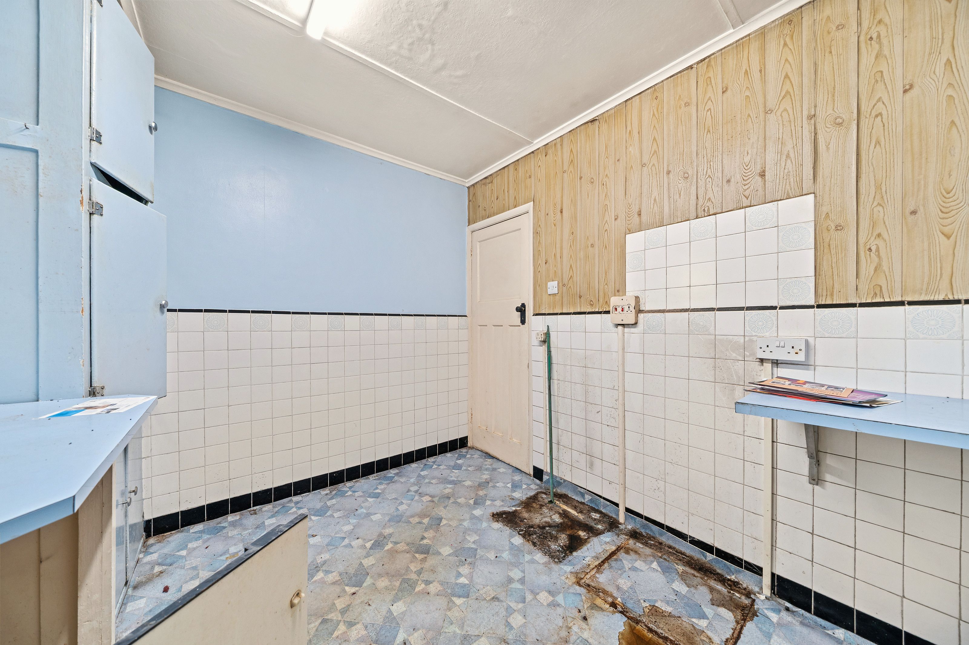 The original kitchen before the work, with white tiling, blue walls and old units