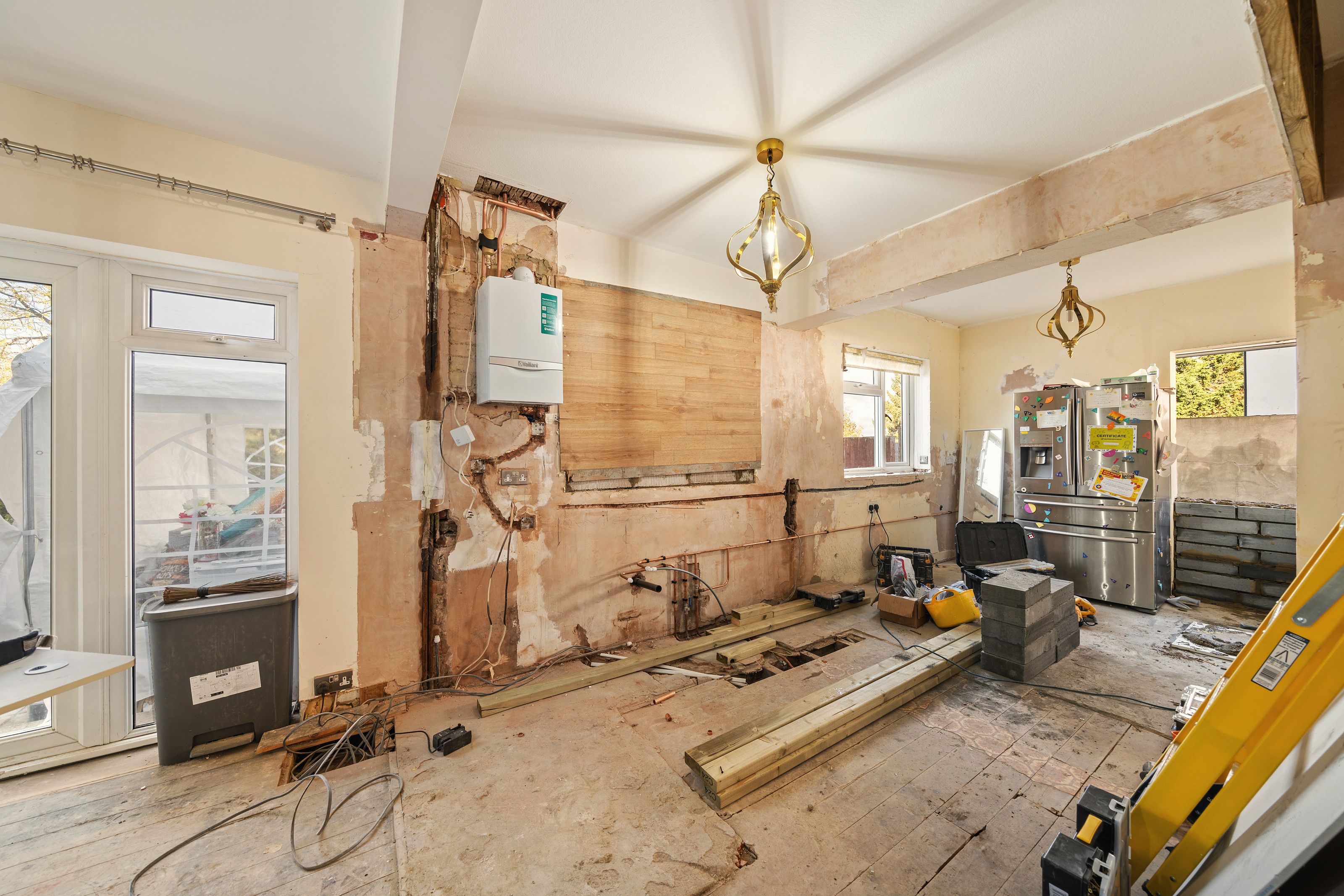 Room before the work with walls opened up and pipework exposed