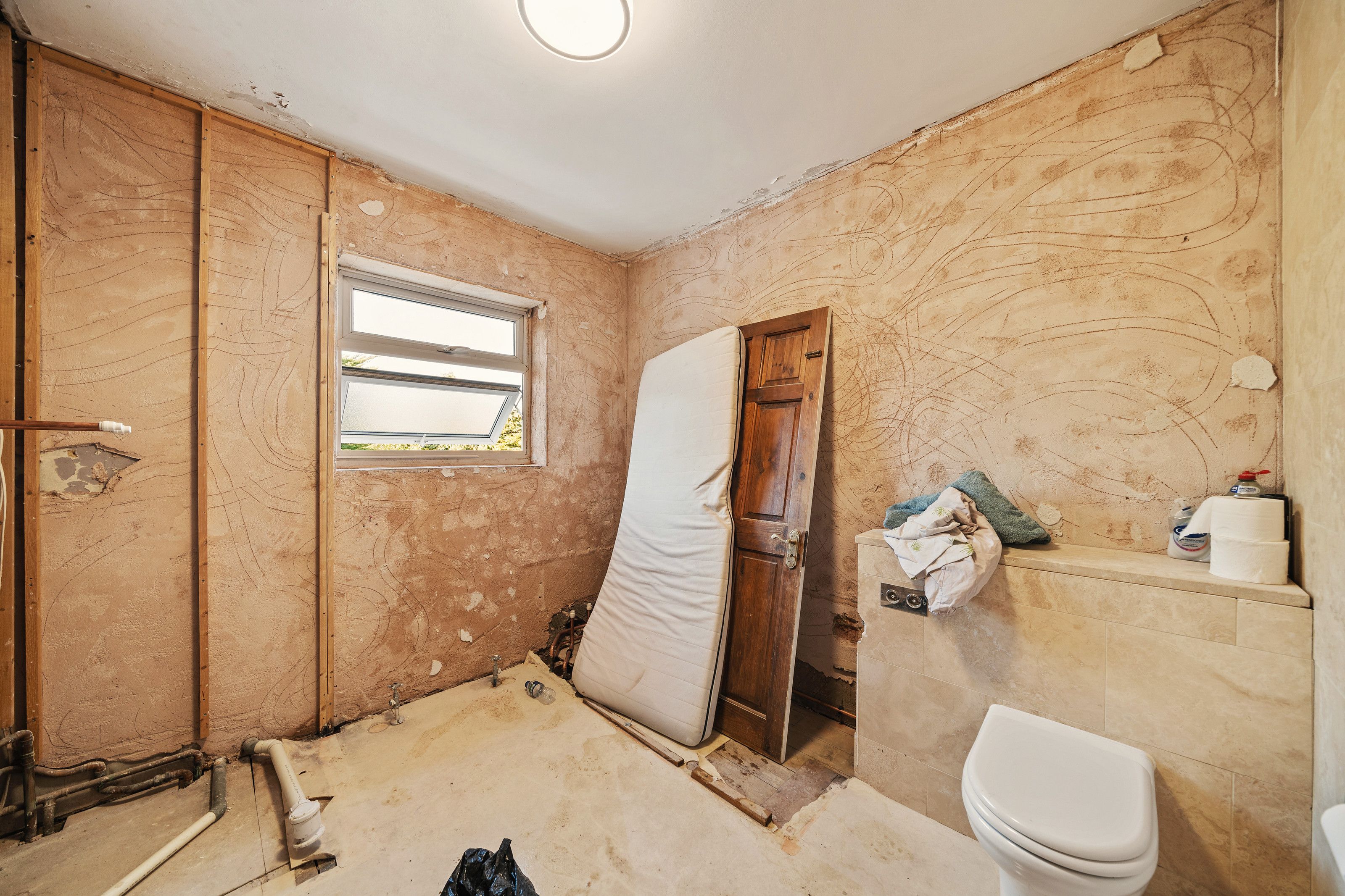 The bathroom stripped back to bare walls before the work