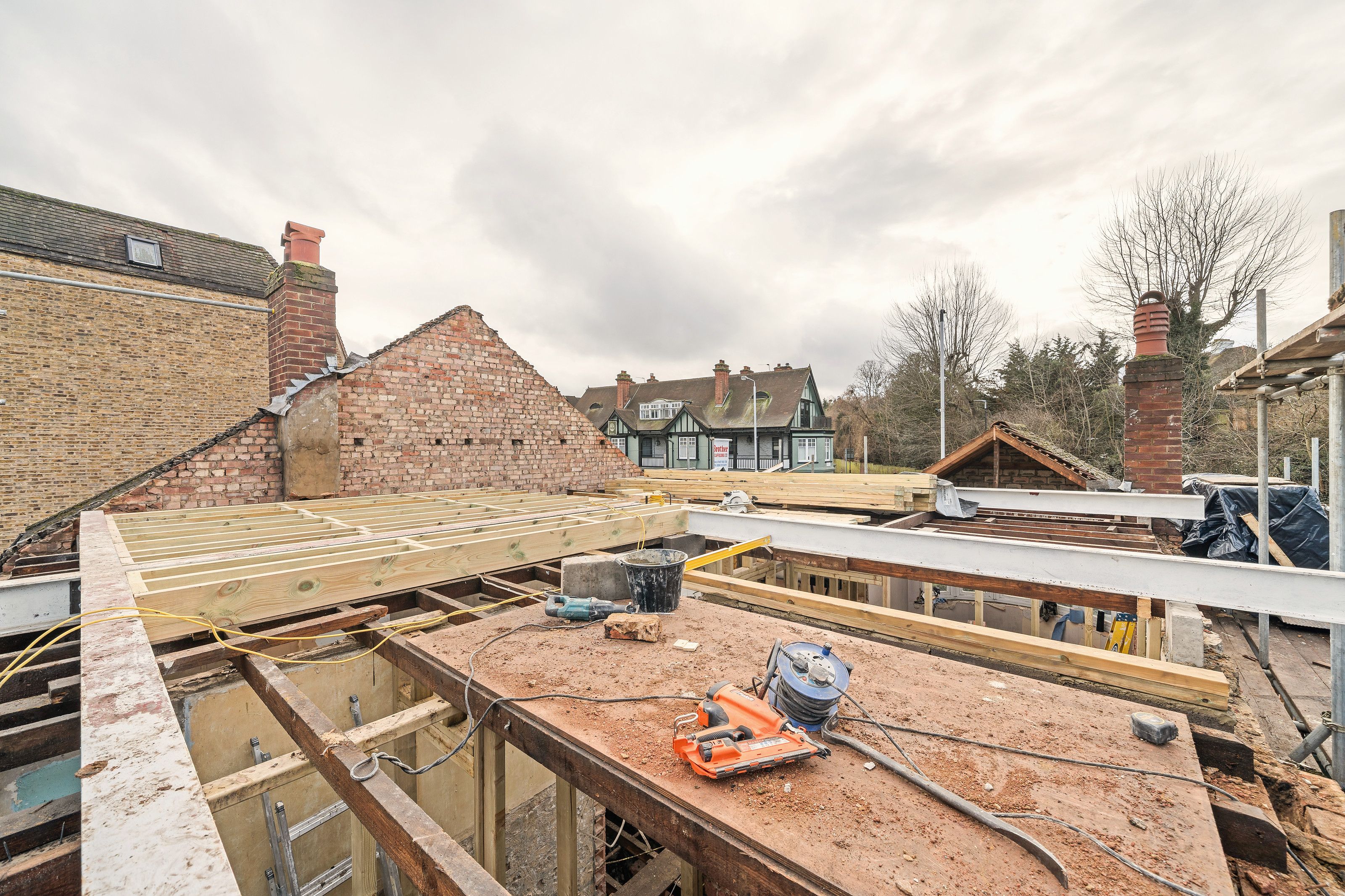 On the new roof structure at scaffold height, with timber joists and boarding and tools laid out