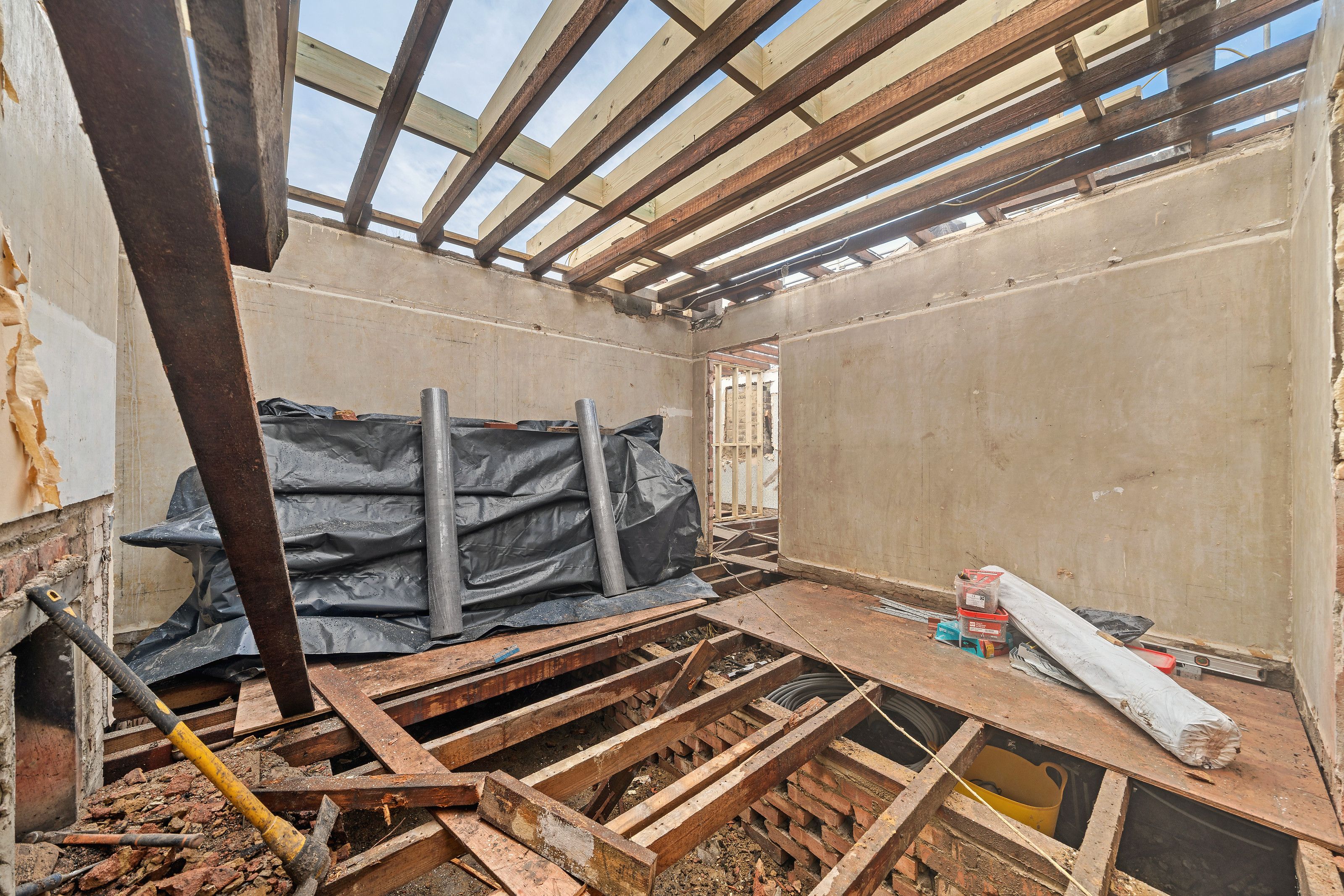 Inside the bungalow with the roof open to the sky and new timbers going in
