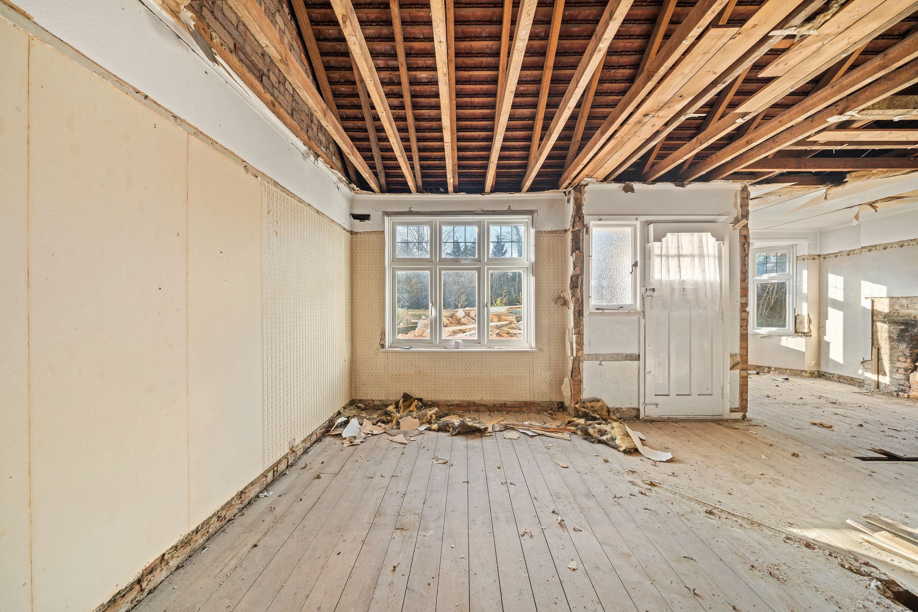 A room stripped back to bare floorboards with the ceiling removed and the joists exposed