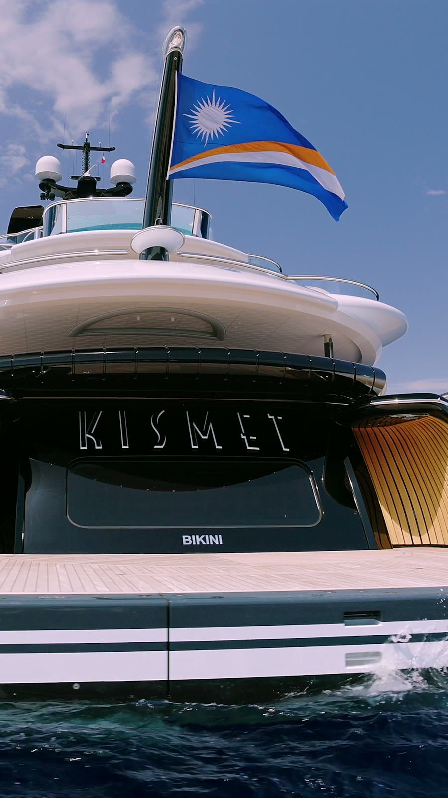 Still from the Kismet reveal film, the yacht's stern and Marshall Islands flag from the water
