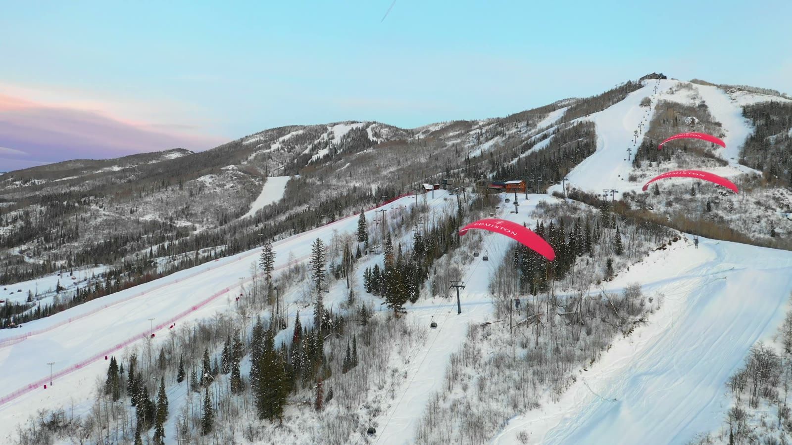 Still from the Edmiston Aspen CGI film, red paragliders carrying the Edmiston name over snowy ski slopes