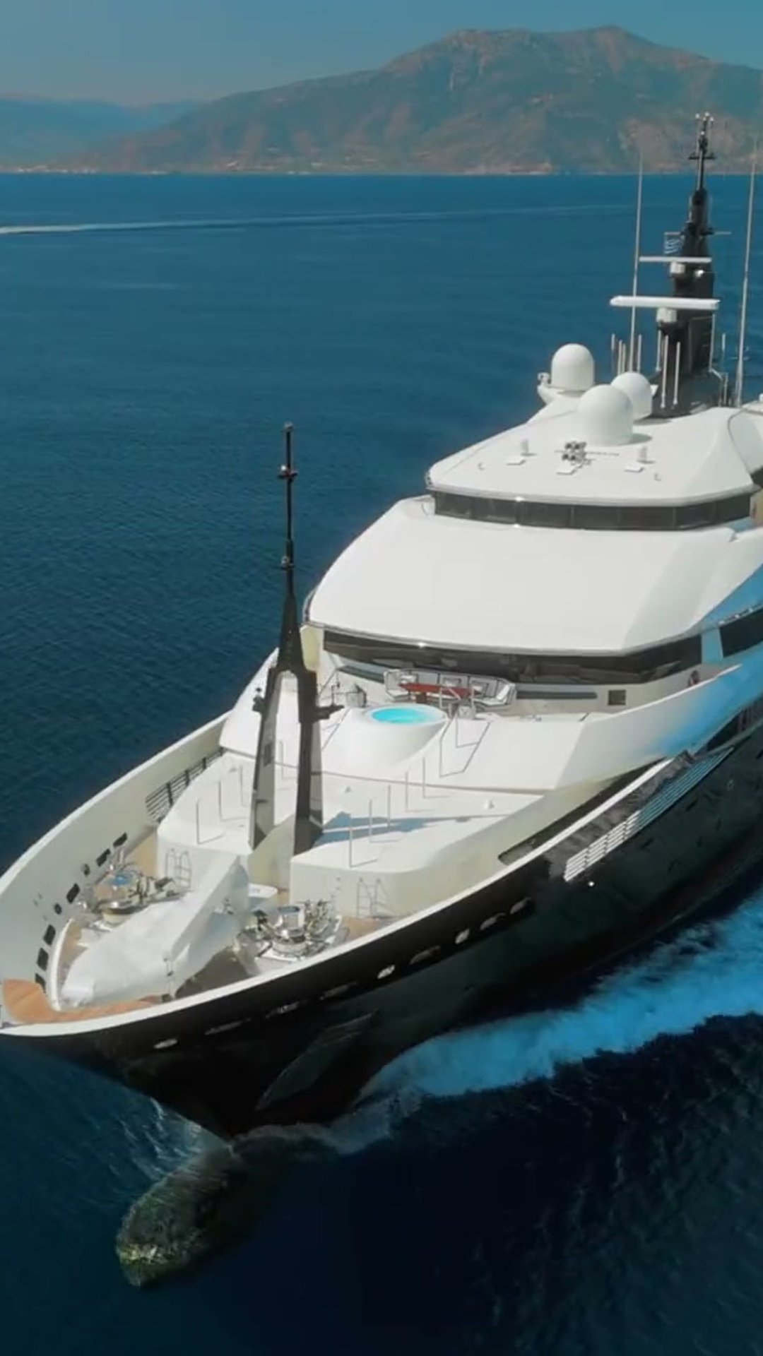 Aerial film still of the superyacht Alfa Nero under way across open blue sea