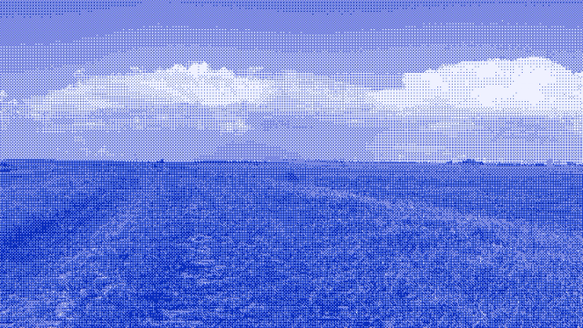 A bank of storm cloud spread across the sky above a dark, open field.