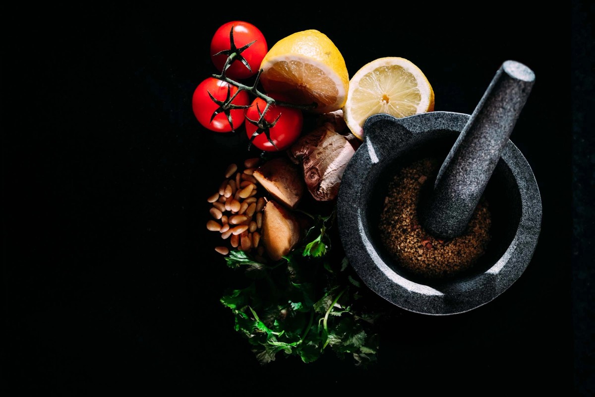 Ingredients gathered around a granite mortar and pestle, not yet combined. The quiet before the cooking starts.
