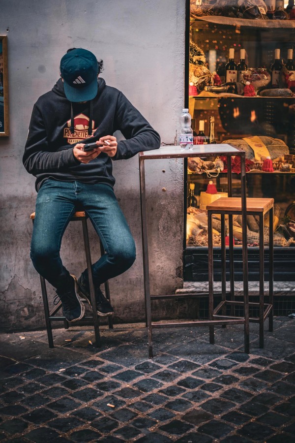 A figure sits Outside a well-stocked Italian deli