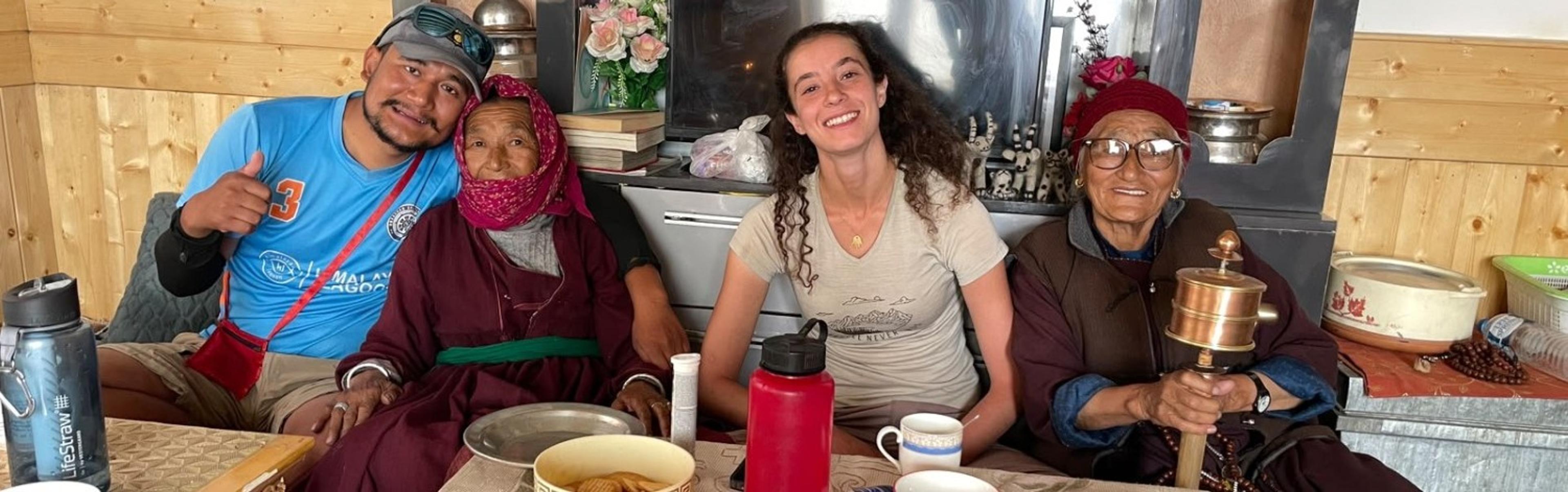 Voyager Ladakh guide and a guest sharing tea with two elderly Ladakhi women in a village home