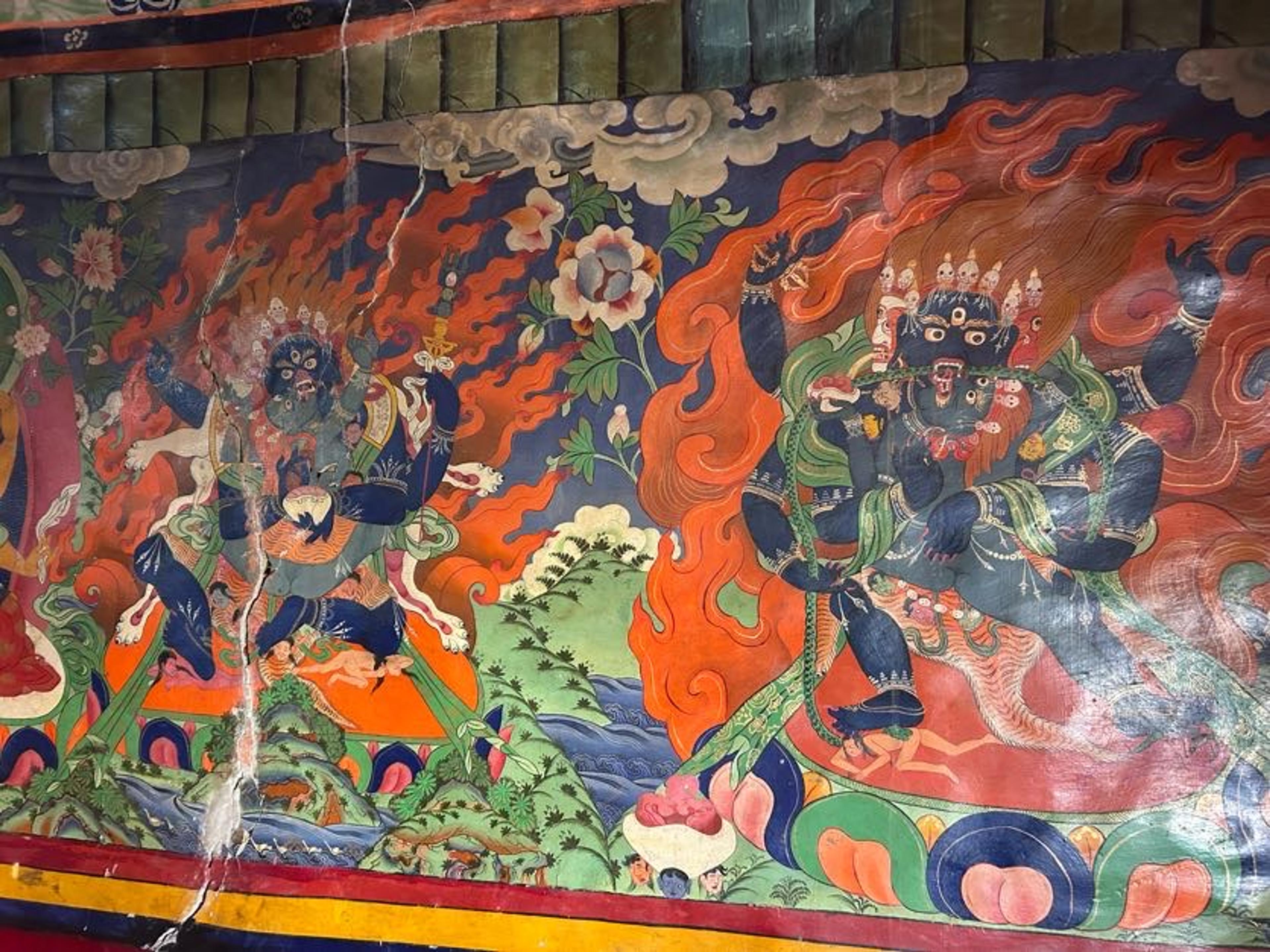 Old monastery wall mural of blue, multi-armed wrathful protector deities surrounded by flames, with cracks in the paint