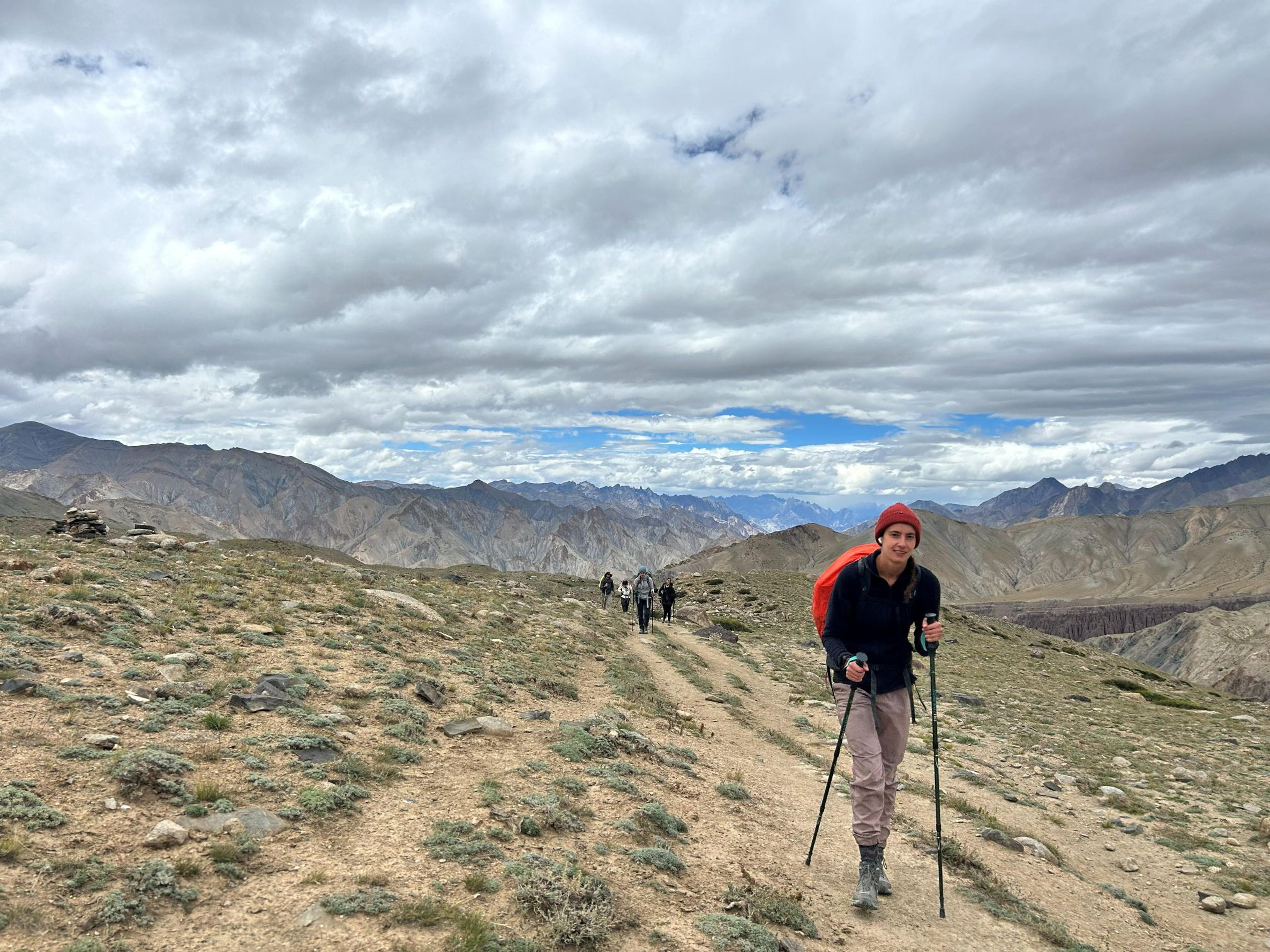 Hiker with trekking poles leading a group along a mountain trail in Ladakh