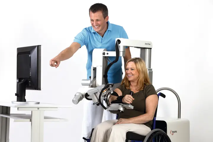 Patiente en rééducation du bras avec l'Arméo Power, accompagnée d'un thérapeute