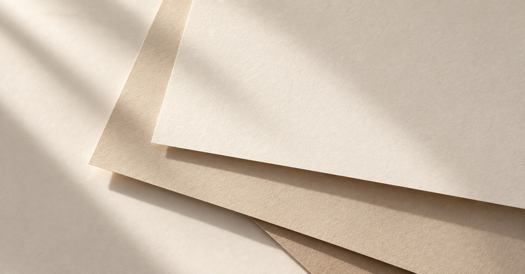 Layers of warm ivory and beige paper overlapping in soft natural light.