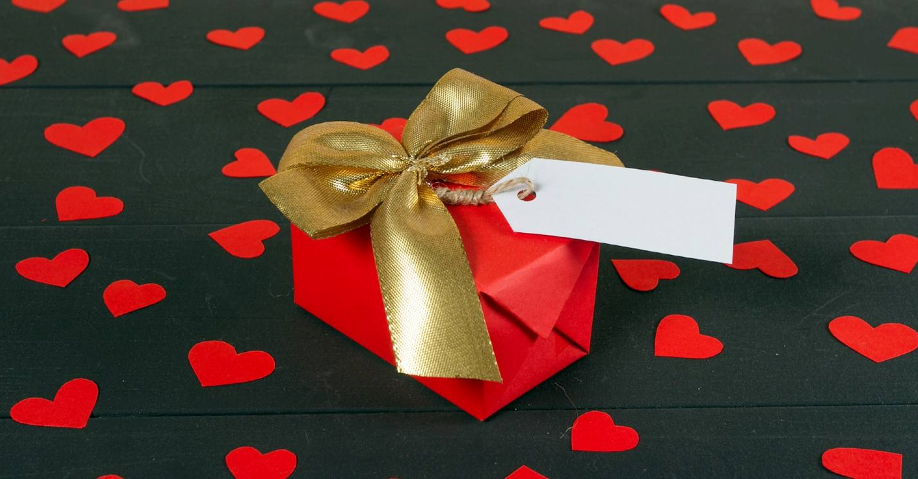 romantisch cadeau in het rood met gouden lint en rode hartjes eromheen