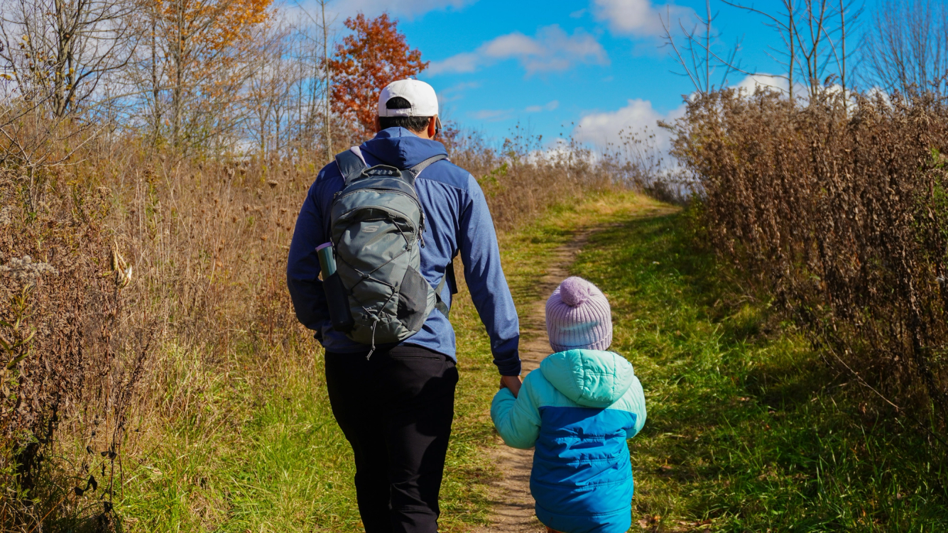 Foto van een vader en een dochter die een wandeling aan het maken zijn.