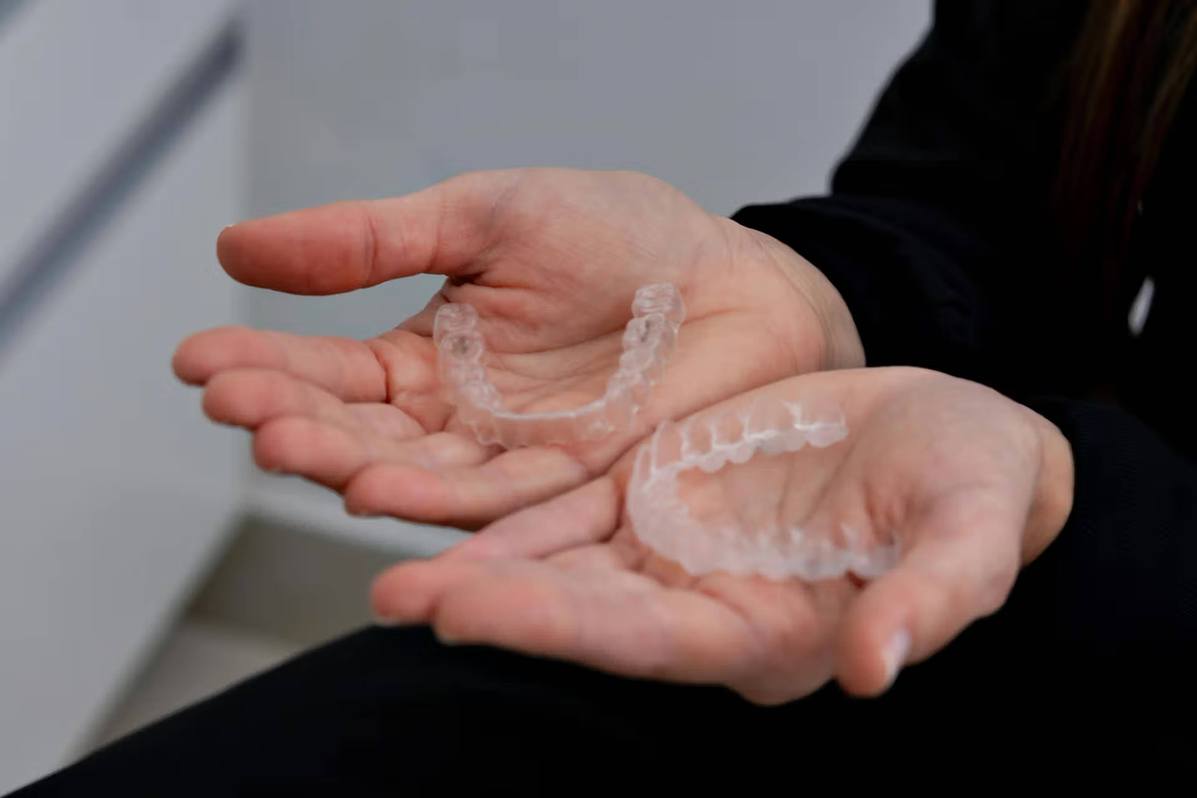 Someone holding a clear mouth guard for bruxism in their hand