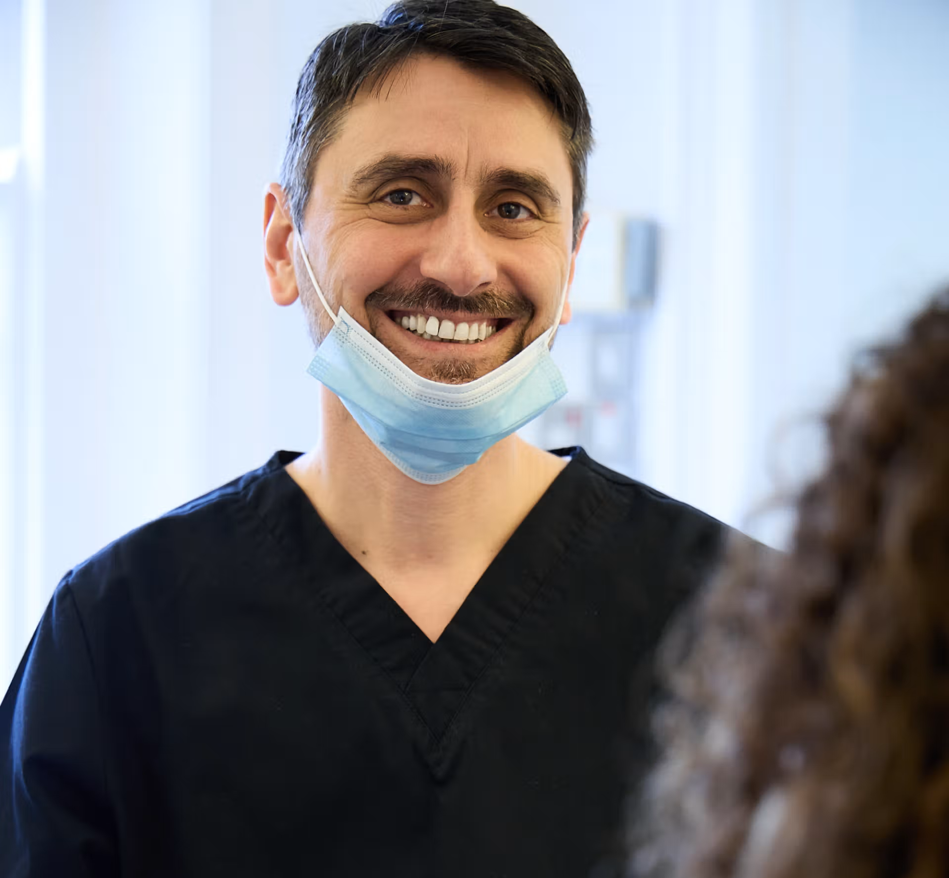 Oreste Gheorghe smiling into the camera while speaking to a patient