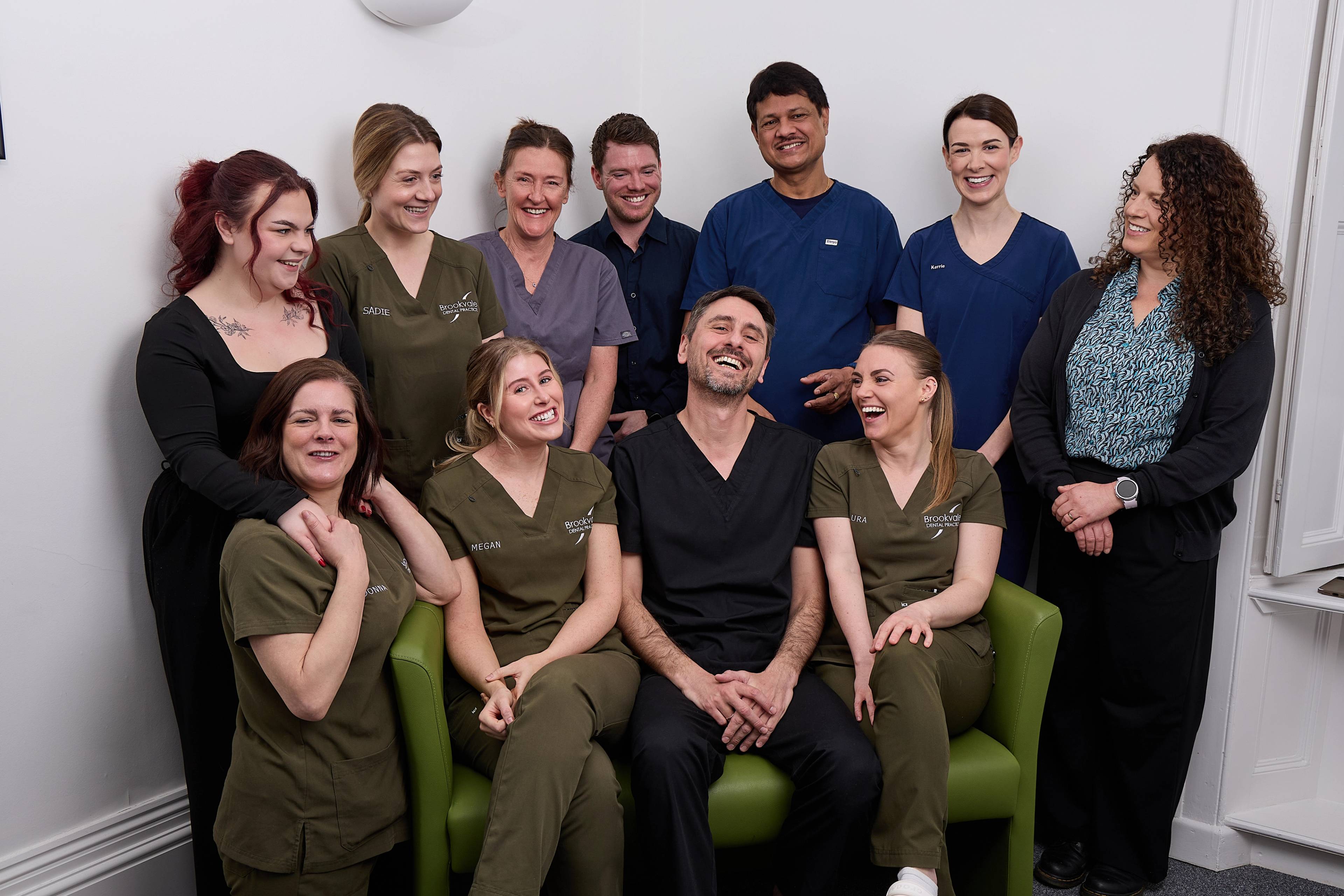 The team laughing together in the practice on a green sofa
