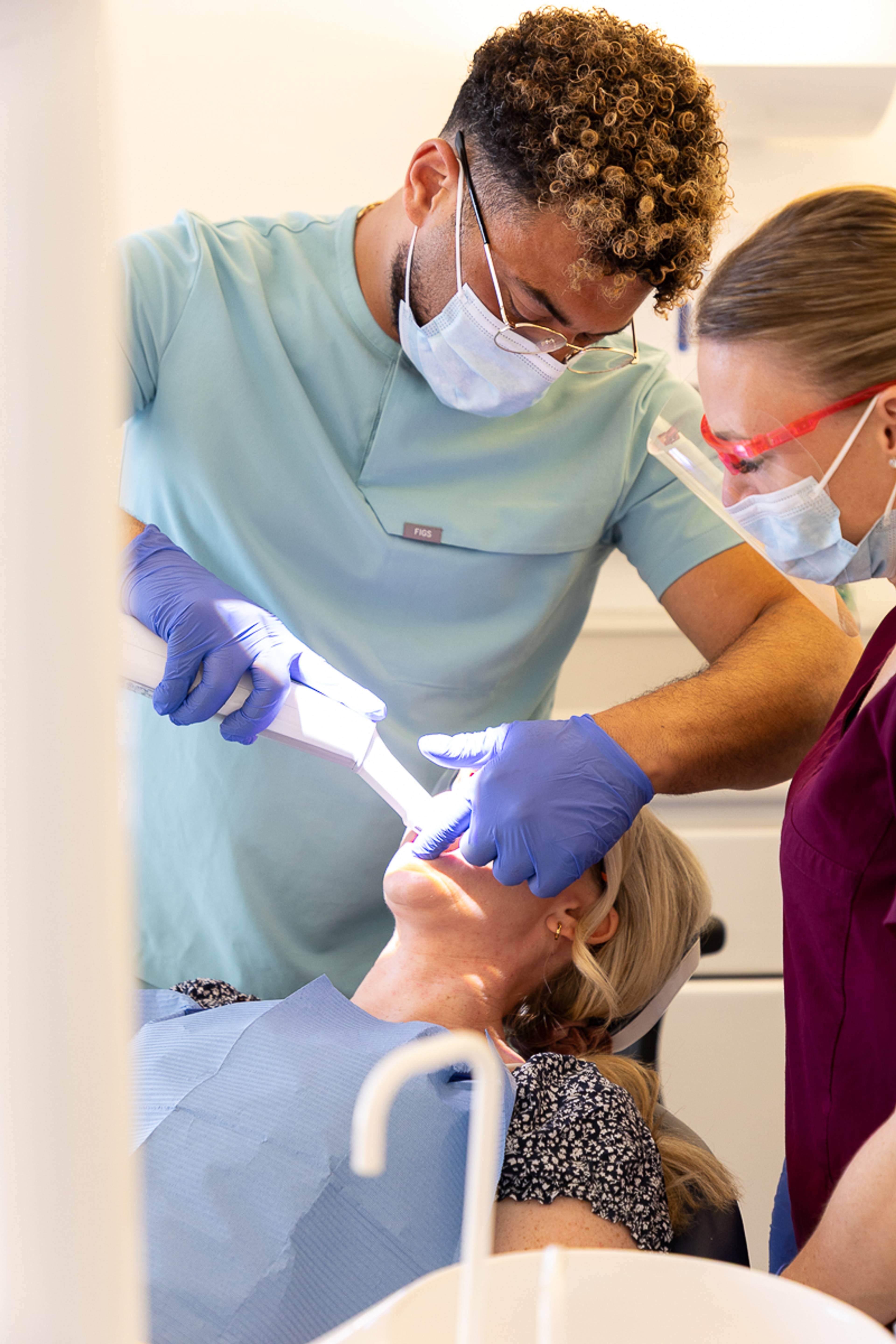 A dentist and dental nurse using an intraoral scanner on a patient