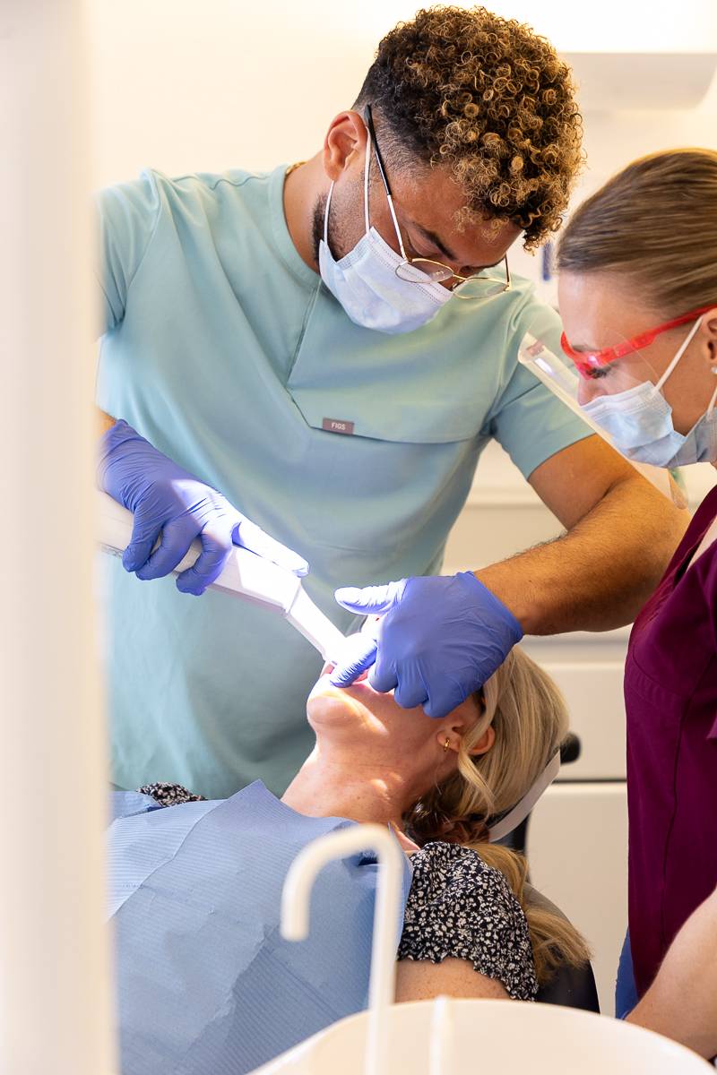 A dentist and dental nurse using an intraoral scanner on a patient