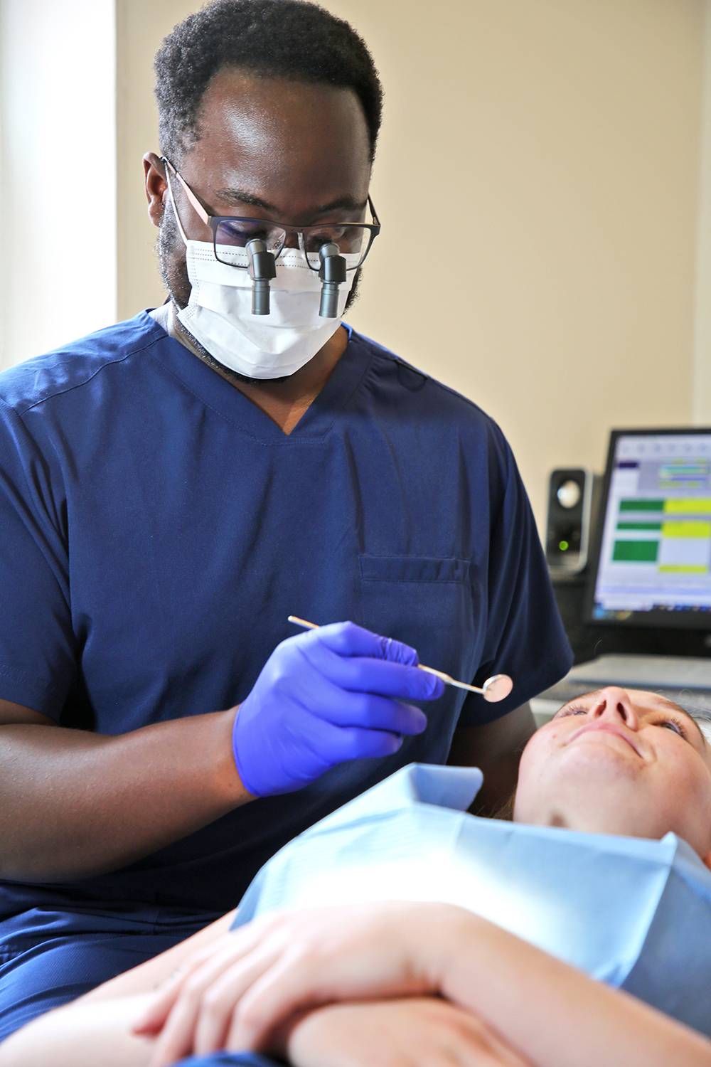Michael Anaman wearing loupes while examining a patient